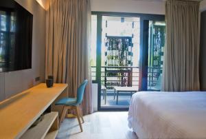 埃斯特角城La Capilla - Punta del Este的一间带一张床和一张书桌的卧室以及一个阳台
