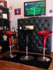 马亚Coffee Cream Guest House Maia的酒吧在电视前设有两个红色凳子