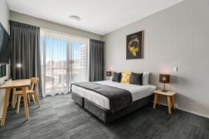 凯恩斯Gilligan's Hotel & Resort Cairns的配有一张床、一张书桌和一扇窗户的酒店客房