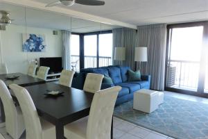 大洋城Sea Watch Condos V的客厅配有桌子和蓝色沙发