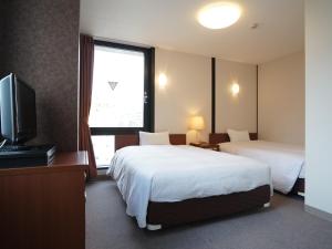 高知高知宫崎富豪酒店的酒店客房设有两张床和一台平面电视。