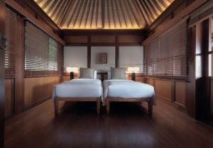 塞米亚克The Legian Seminyak, Bali的配有木墙和窗户的客房内的两张床