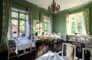 AlvesloheHotel & Gästehaus Gut Kaden的用餐室设有白色的桌子和窗户。