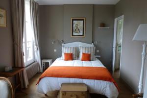 奥登河畔的布雷特维尔Chambres d'Hôtes Le Bas Manoir的一间卧室配有一张带橙色枕头的大床