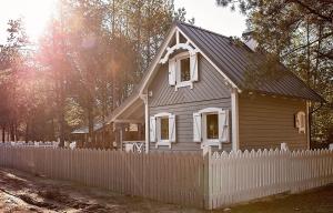 BartoszylasLeśna Osada na Kaszubach - drewniane domy na wynajem的白色栅栏后面的小房子