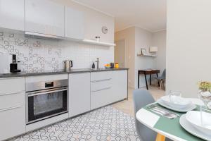 格但斯克Platinum Tartaczna Apartments by Renters的厨房配有白色橱柜和餐桌