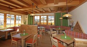 拉姆绍达赫斯坦阿尔彭佩乐旅馆的餐厅设有木桌、椅子和窗户。