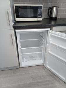 莱瑟姆-圣安妮St Annes Lodge Apartments, Lytham St Annes的厨房配有微波炉和空冰箱。
