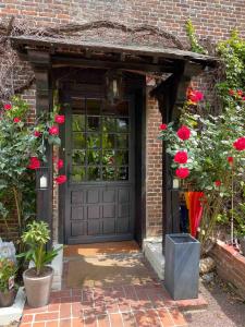 Saint-Aubin-le-VertueuxLe Moulin Fouret的黑色车库门,有红色的花朵和玫瑰