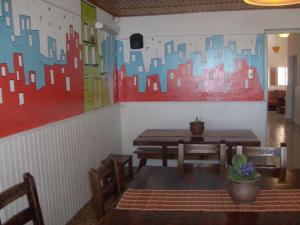 圣拉斐尔香提旅舍的餐厅设有桌椅,墙上挂有绘画作品