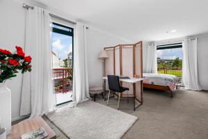 Te WhangaHarbourside Haven - Whangaparāoa Studio Apartment的一间卧室配有一张床、一张桌子和窗户