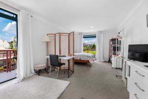 Te WhangaHarbourside Haven - Whangaparāoa Studio Apartment的白色的客房设有一间卧室、一张床和一张桌子