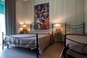 安齐奥Alloggi Villa Sarsina的配有两张床铺的客房配有两盏灯和一幅画