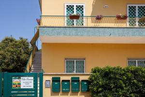 安齐奥Alloggi Villa Sarsina的黄色的建筑,设有绿色的门和阳台
