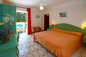 伊斯基亚卡里托公园酒店的一间卧室配有一张带橙色床罩的床