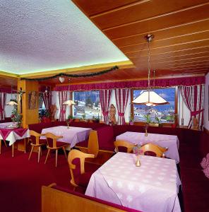 塞尔瓦迪加尔代纳山谷瓦尔酒店的餐厅设有白色的桌椅和窗户。