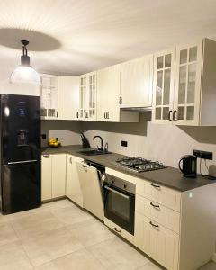 ZalesieDom Malowy Sad的厨房配有白色橱柜和黑色冰箱。