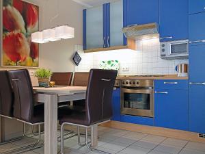 诺德代希Apartment Witthuus-Norderney by Interhome的厨房配有蓝色橱柜和桌椅