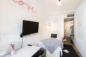 皮兰塔迪尼艺术酒店的白色卧室设有一张床和墙上的电视