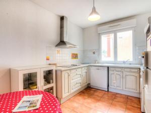 卡布勒通Apartment les Terrasses du Cap by Interhome的厨房配有白色橱柜和红色桌子