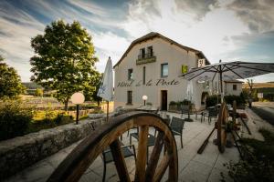 Châteauneuf-de-RandonHôtel Restaurant de la Poste et La Grange Détente, espace bien-être的前面有桌子和伞的建筑