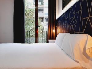 巴塞罗那Hostal Laia by gaiarooms的卧室配有白色的床和窗户。