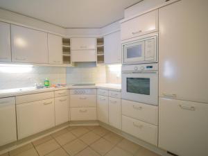 采尔马特Apartment Bergere-1 by Interhome的白色的厨房配有白色的橱柜和微波炉