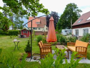 胡芬根Holiday Home Schmetterlingsgarten by Interhome的庭院配有橙色遮阳伞、椅子和桌子