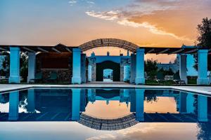 奥斯图尼Masseria Ayroldi的一座享有日落美景的建筑前的游泳池