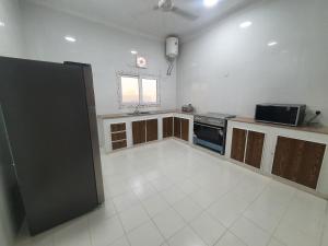 Ma‘ābīlahشاليه الشهد的厨房配有黑色冰箱和白色瓷砖地板。