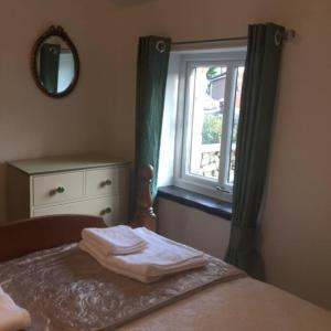 塞德伯Dalesway cottage的一间卧室配有一张带窗户和镜子的床