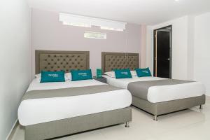 麦德林Ayenda 79 Hotel的卧室内的两张床和蓝色枕头