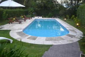 贝尔格拉诺将军镇Casa Simona Villa General Belgrano的庭院内的游泳池配有长椅和遮阳伞