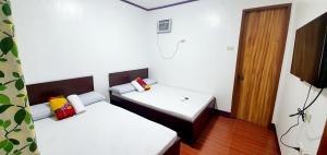曼巴豪SJ Pabua Travellers Inn的小房间设有两张床和一扇门