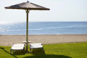 法里拉基阿波罗海滩酒店的海滩上的两把椅子和一把遮阳伞