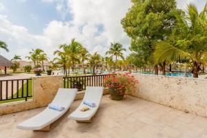 蓬塔卡纳Luxe 1 BR Cap Cana, DR - Steps Away From Pool, King Bed, Caribbean Paradise!的庭院设有两把白色椅子和围栏