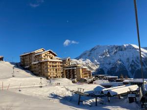 奥尔西埃Appartement 6 places aux pieds des pistes avec piscine, wifi et parking privé PMR的一座雪地中的建筑,背景是一座山