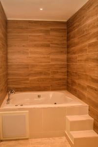 拉罗马纳Halibut Hotel的带浴缸的浴室,设有木墙