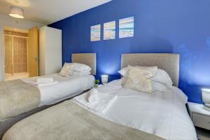 北安普敦City Centre Apartment with Secure Parking by MBiZ的卧室设有两张床铺,拥有蓝色的墙壁