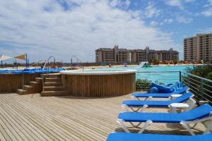 阿尔加罗沃Laguna Bahía Fernanda的一个带椅子的海滩和一个带游乐场的游泳池