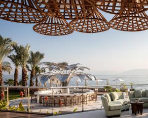 提比里亚Galei Kinneret Hotel的一个带桌椅的海景庭院