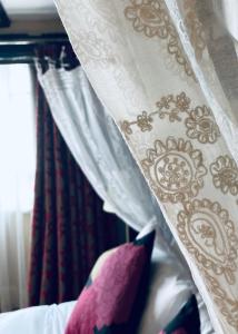 坎特伯雷艾格尼丝之家酒店的床上的白色窗帘和紫色枕头