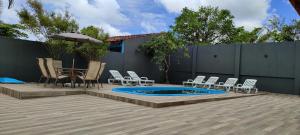 伊塔波阿Lindo Sobrado c/ Piscina e conforto próximo do mar的一个带椅子的庭院和一个带遮阳伞的游泳池