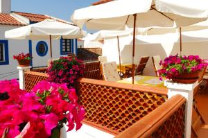 米尔芳提斯城阿德鲁之家旅馆的阳台配有鲜花、桌子和雨伞。