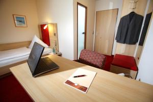 莱茵河畔凯尔Hotel Schwanen的客房设有一张桌子和一台笔记本电脑