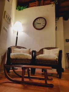 阿巴迪亚圣萨尔瓦托雷La Tana del Riccio的两把椅子和一张桌子,墙上挂着时钟