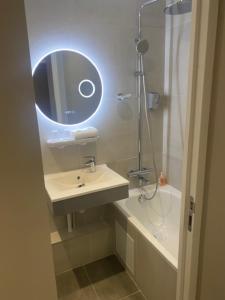 巴黎圣皮埃尔酒店的浴室配有盥洗盆、镜子和浴缸
