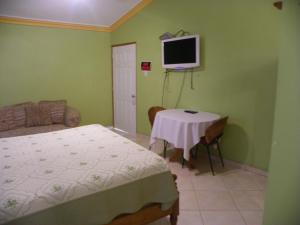 太子港Pavillon Des Receptions & Hotel的一间卧室配有一张床、一张桌子和一台电视。
