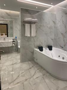 吉达Temandra Hotel的白色的浴室设有浴缸和水槽。