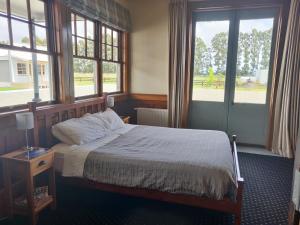 朗伊奥拉Bramley's Stables and Accommodation的一间卧室配有床、两扇窗户和一张四柱床